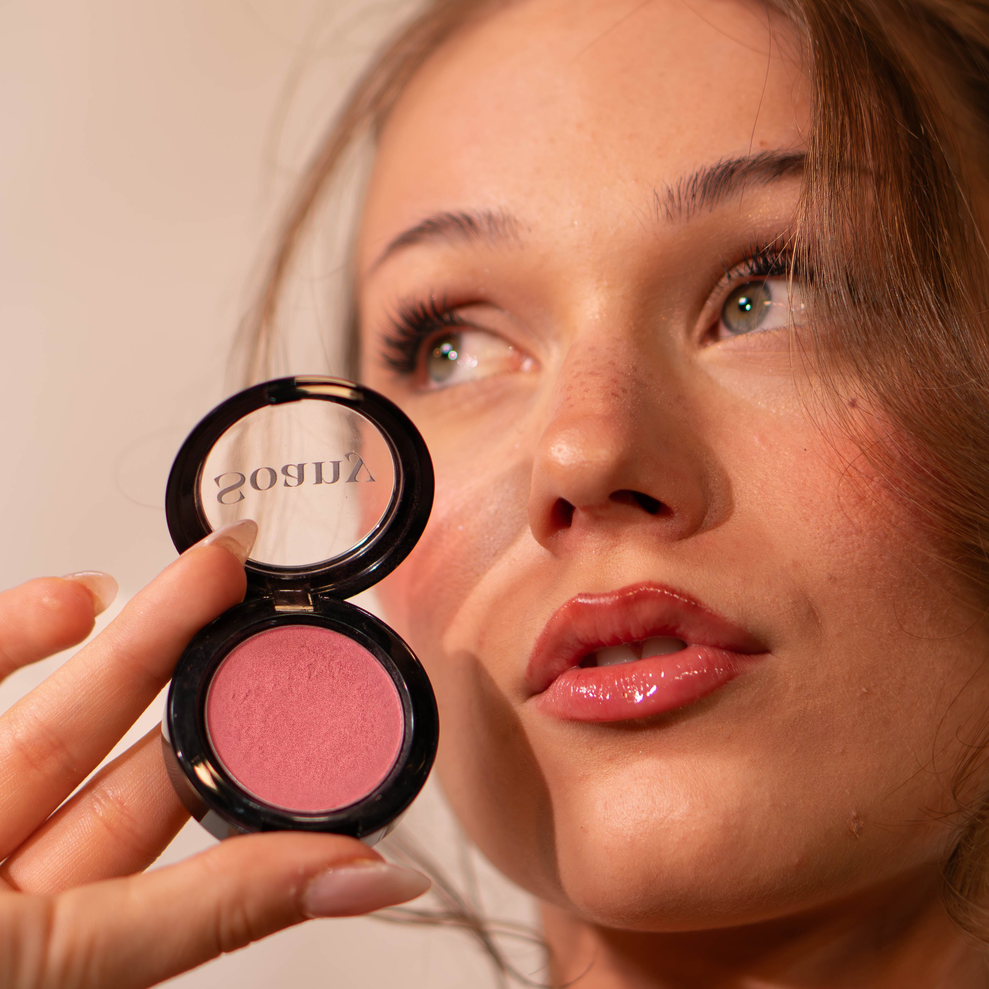Woman holding a compact blush with a visible Soany logo.